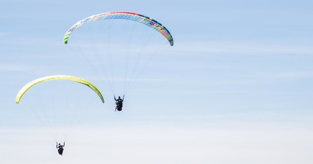 Paragliders soaring over clear blue sky above alpine valley
