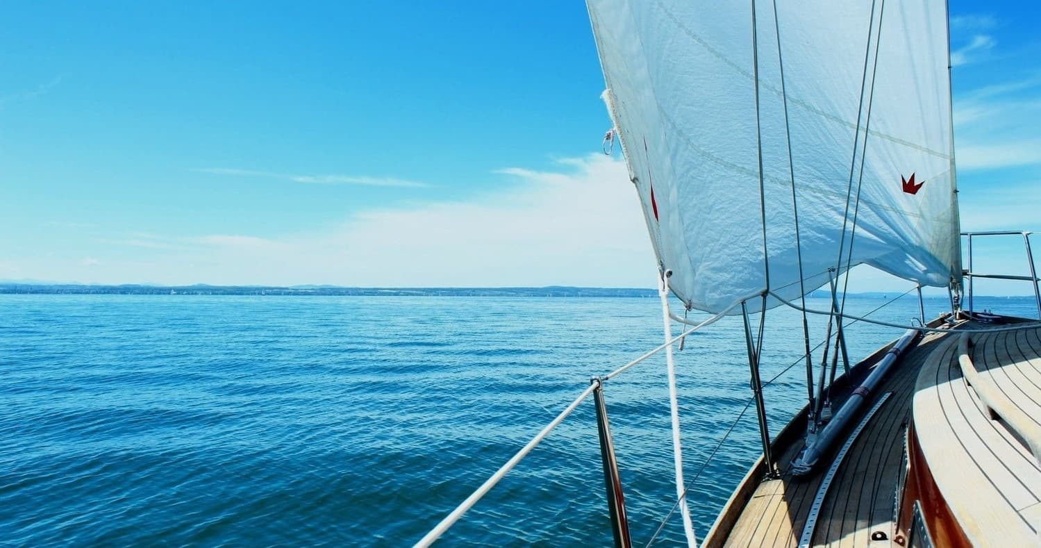 Sailing bow gliding across open ocean under clear blue sky