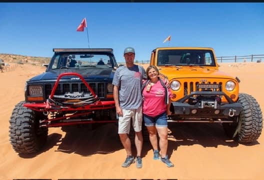 Couple posing with modified Jeeps on red sand dunes adventure