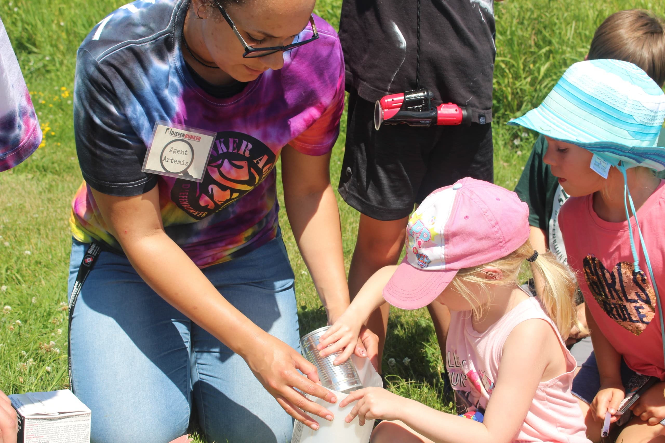 Children exploring outdoor science activity at summer camp field