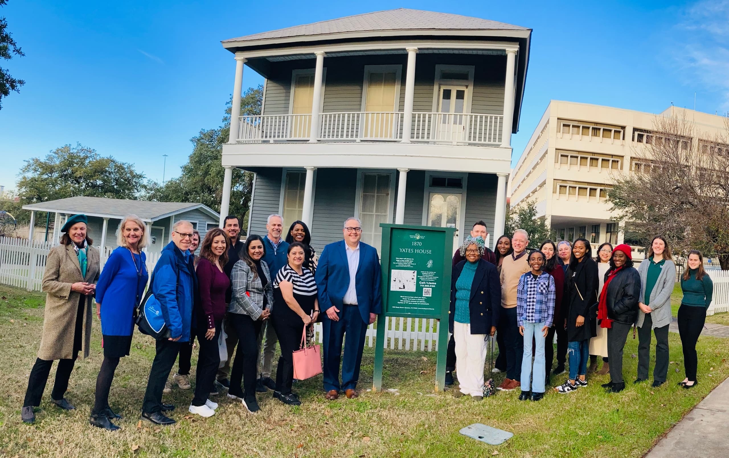 Large group posing outside historic home at Sam Houston Park