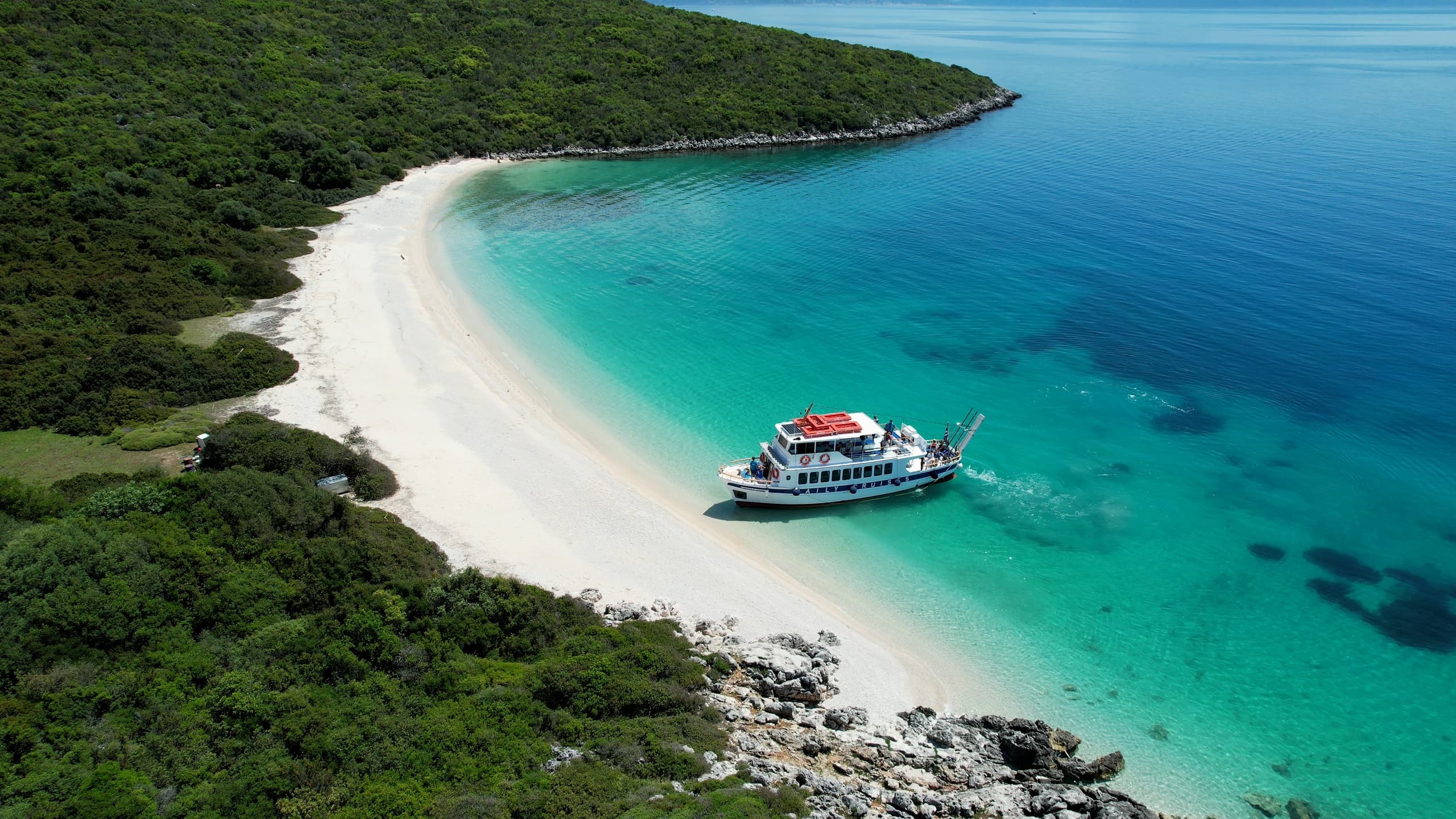 Coastal cruise anchored at turquoise secluded beach for island stop