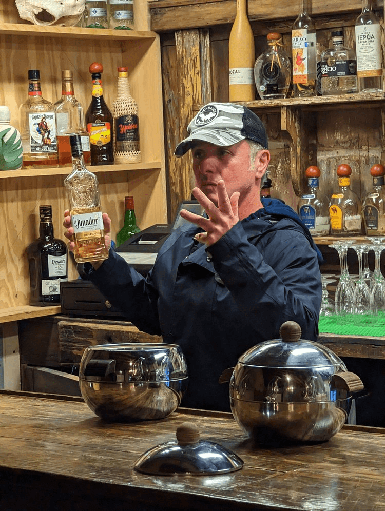 Guide presenting tequila bottles inside rustic desert bar tasting room