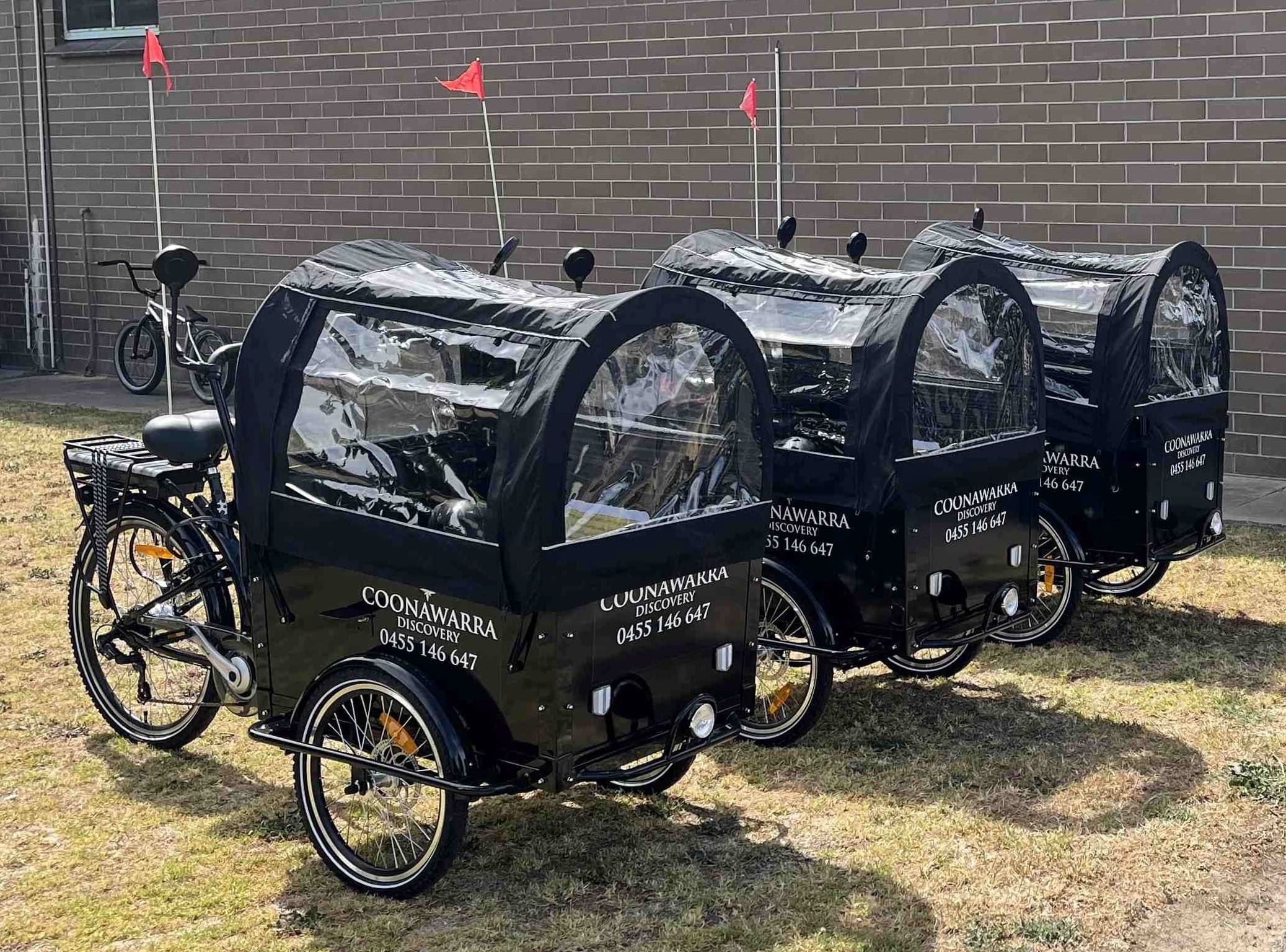Covered cargo bikes parked on grass for Coonawarra bike tours