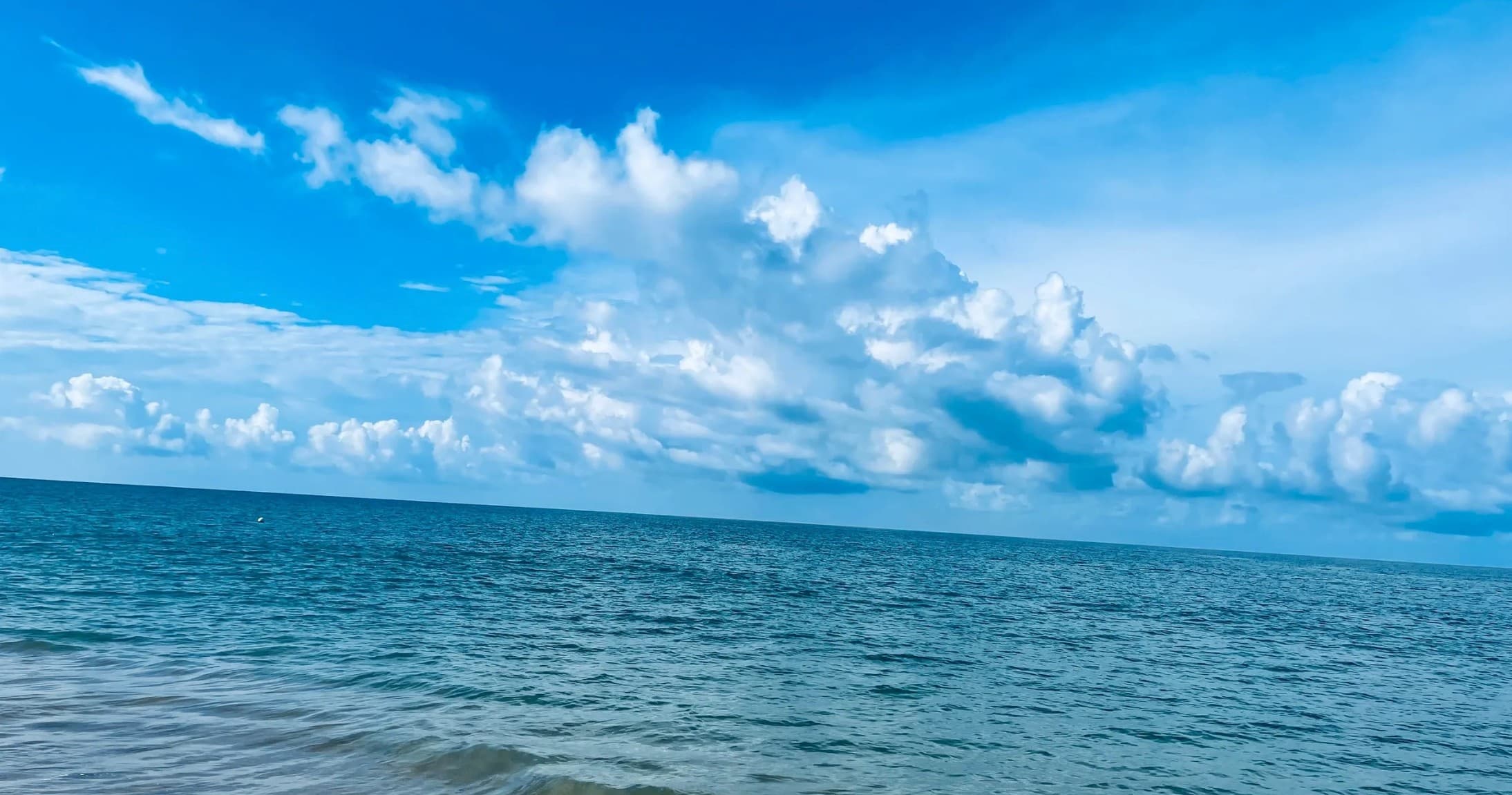 Calm ocean horizon with blue sky for beach charter views