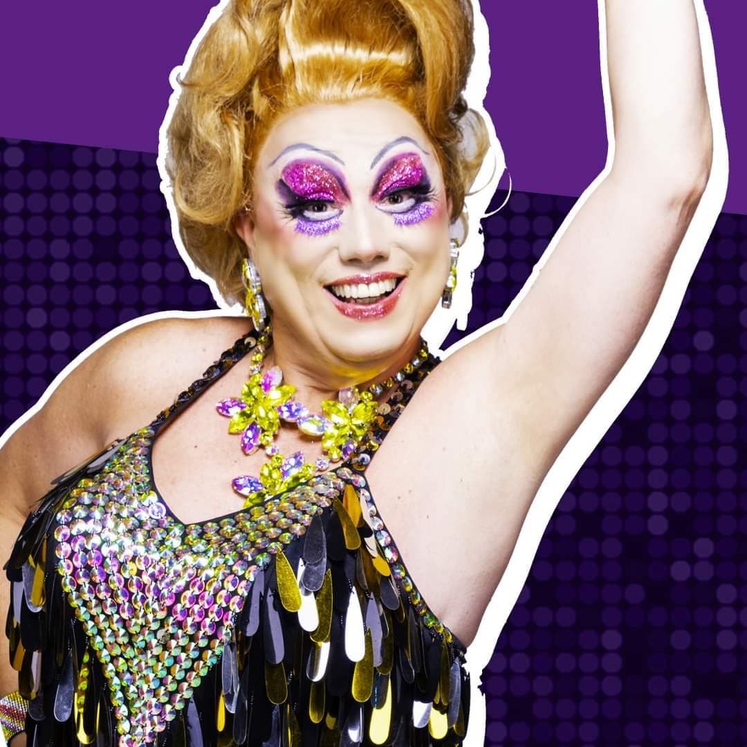 Drag performer in colorful makeup and costume on nightclub stage