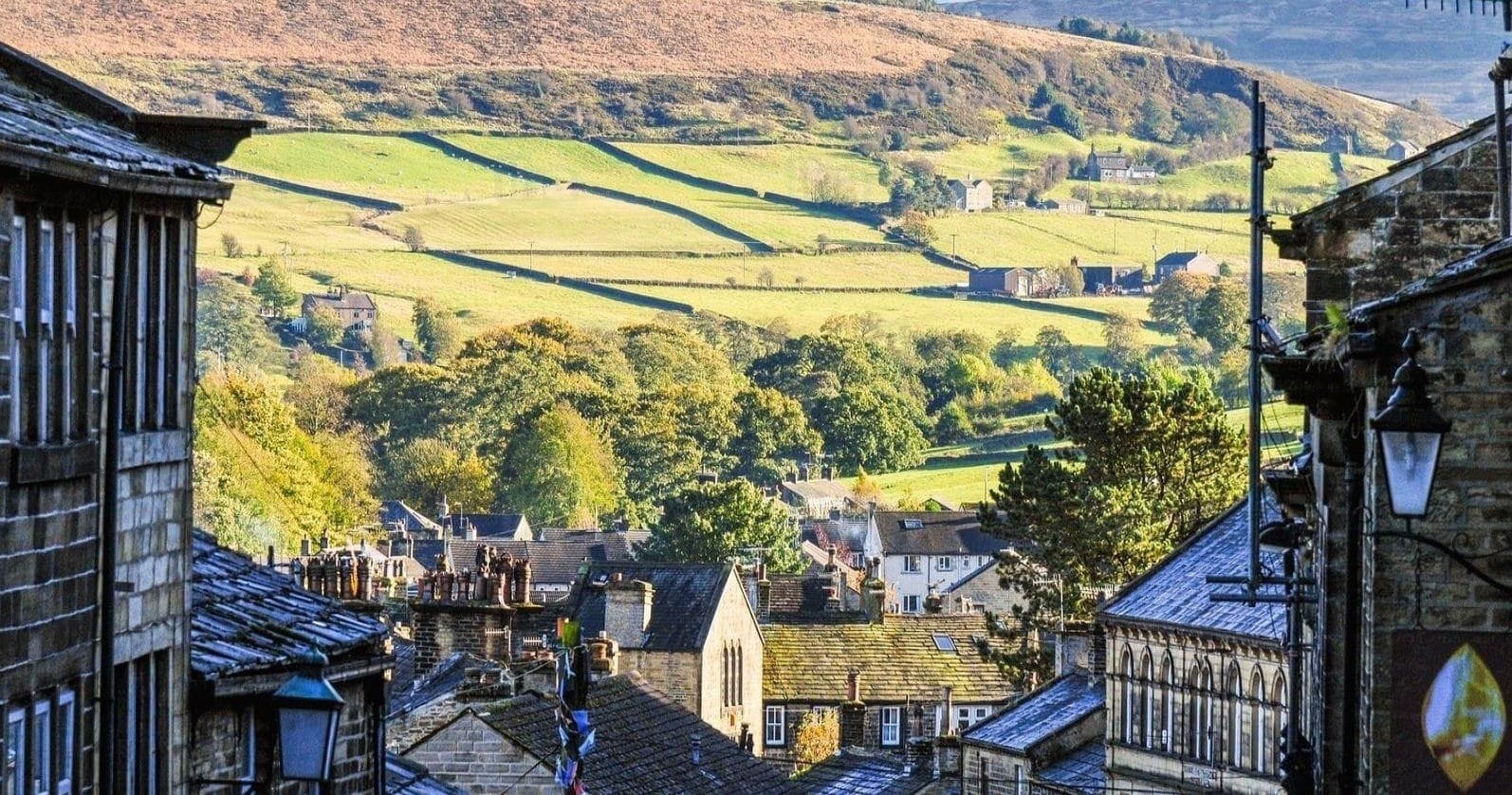 Cobblestone high street opening to green valleys and distant hills