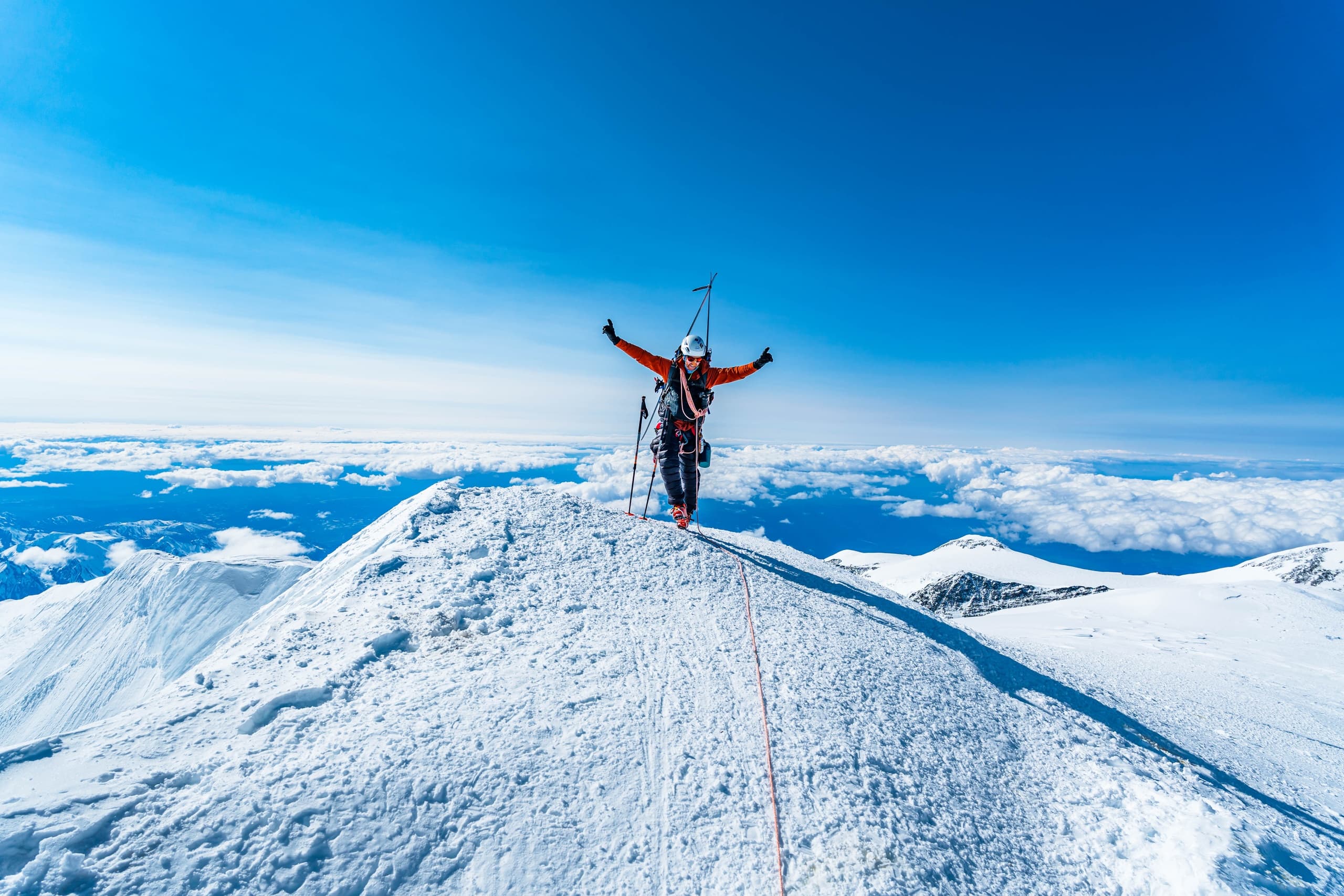 Mountaineer summiting snowy peak, high-altitude alpine ascent