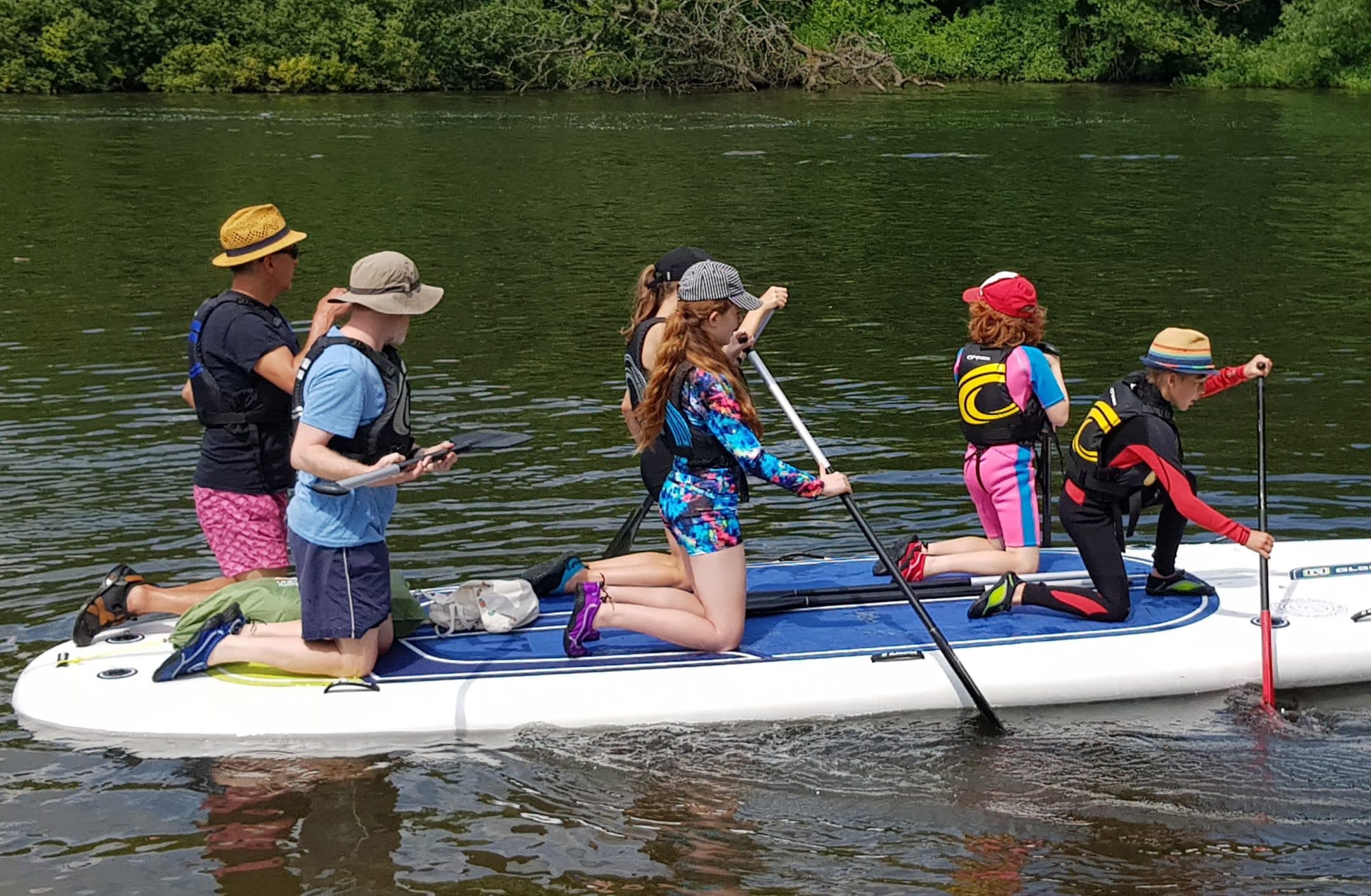 Group of family paddleboarders on calm river enjoying summer outing
