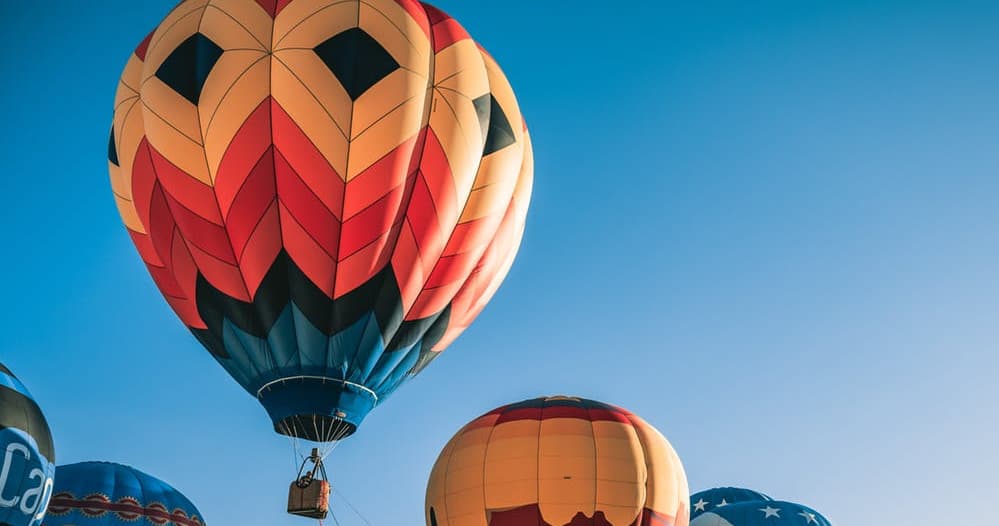 Group of vibrant hot air balloons ascending into clear sky