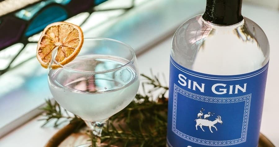 Gin cocktail and bottle on bar near stained-glass window