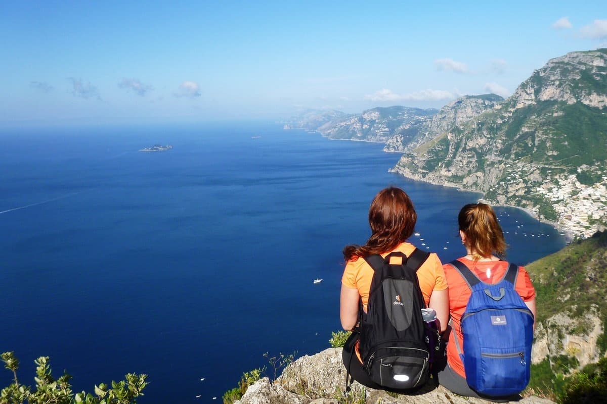 Two hikers sitting on cliff overlooking the Amalfi Coast