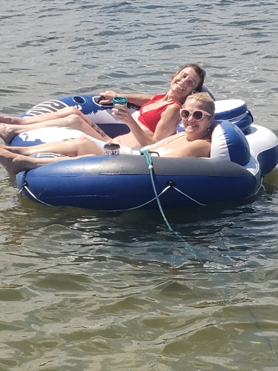 Friends tubing on inflatable raft in shallow lake water
