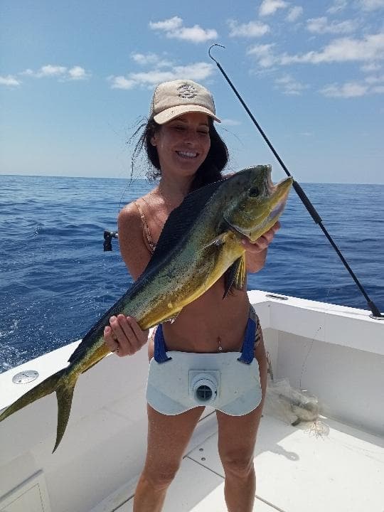 Woman holding freshly caught mahi-mahi on deck of sportfishing boat
