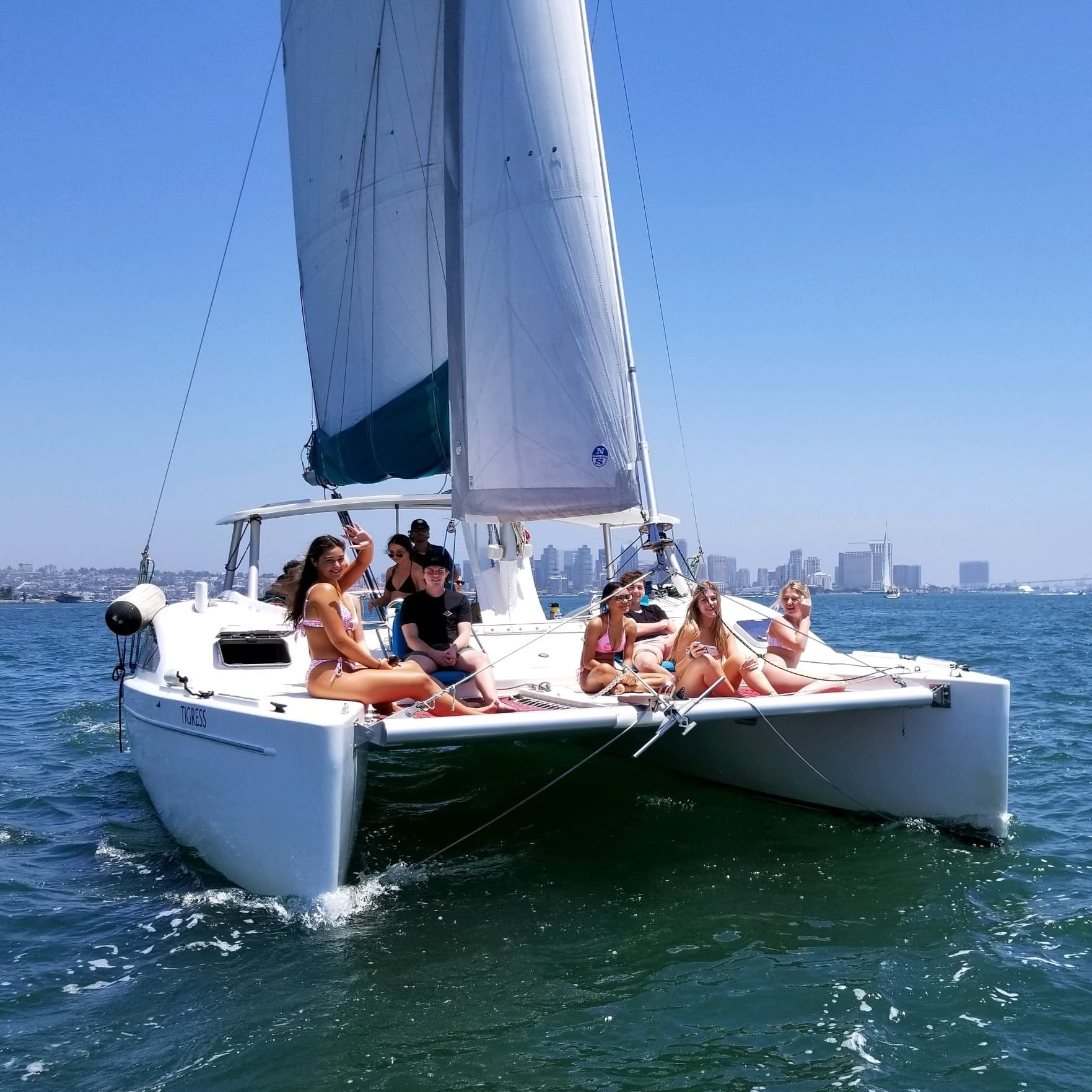 Friends on catamaran sailing near city skyline on sunny day