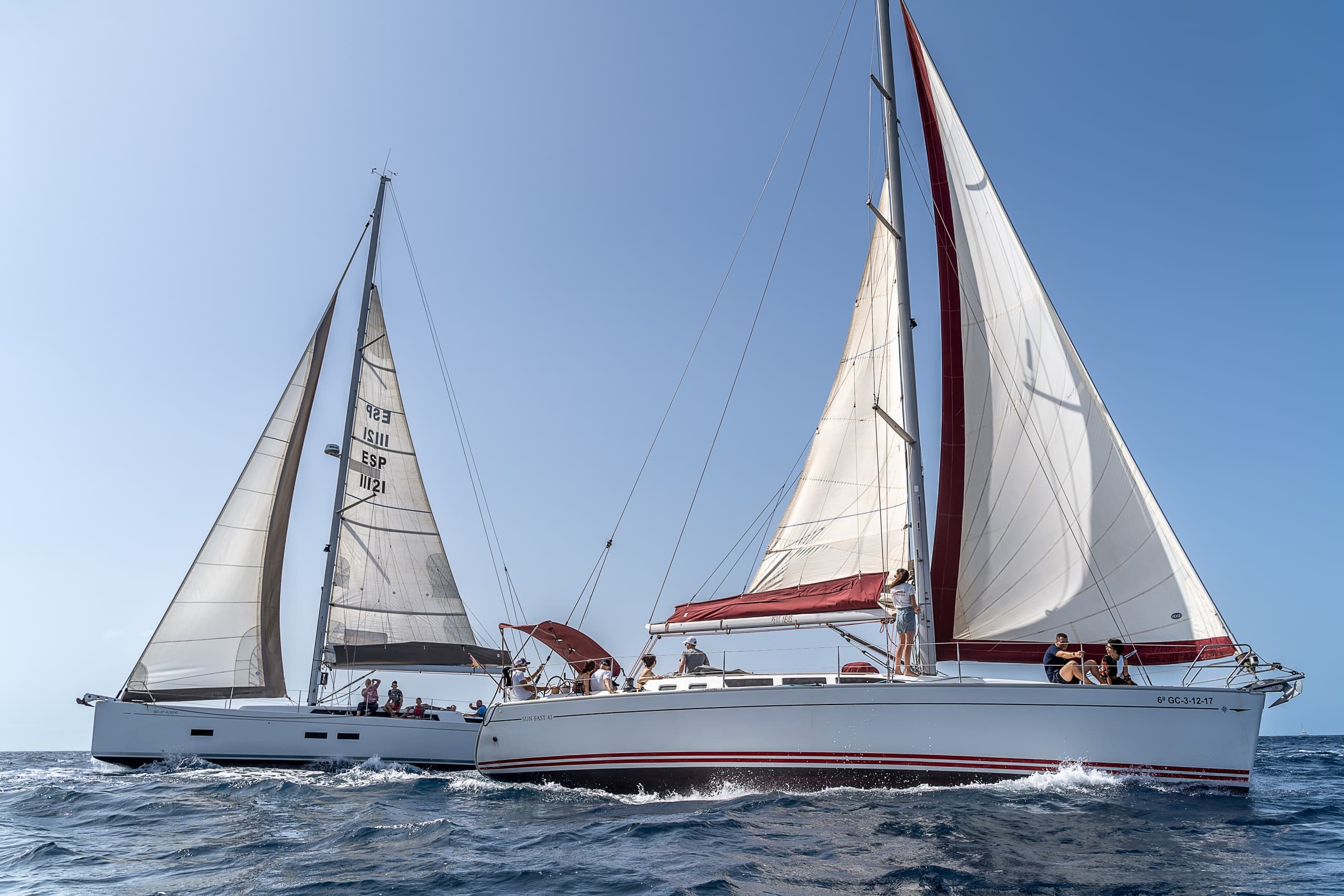 Two sailing yachts under sail on open ocean near coast