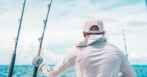 Angler at stern casting lines into open ocean during charter