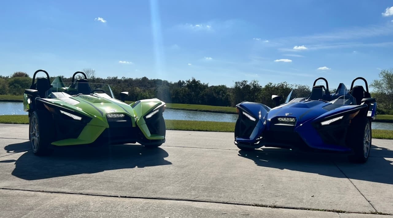 Two open-air Slingshot roadsters parked lakeside for scenic drive