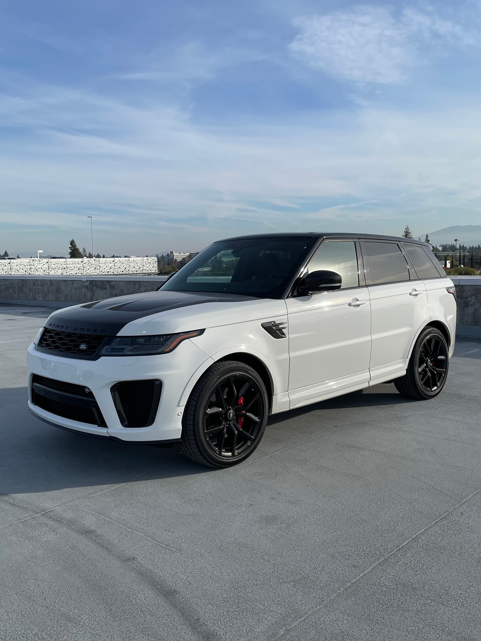 White Range Rover Sport parked on rooftop with expansive sky view