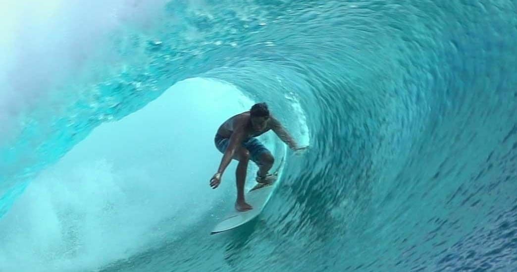 Surfer riding a blue ocean barrel wave on reef break