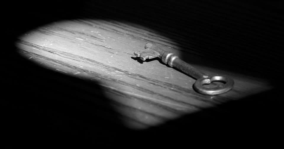 Antique key on wooden floor in spotlight, mystery escape clue