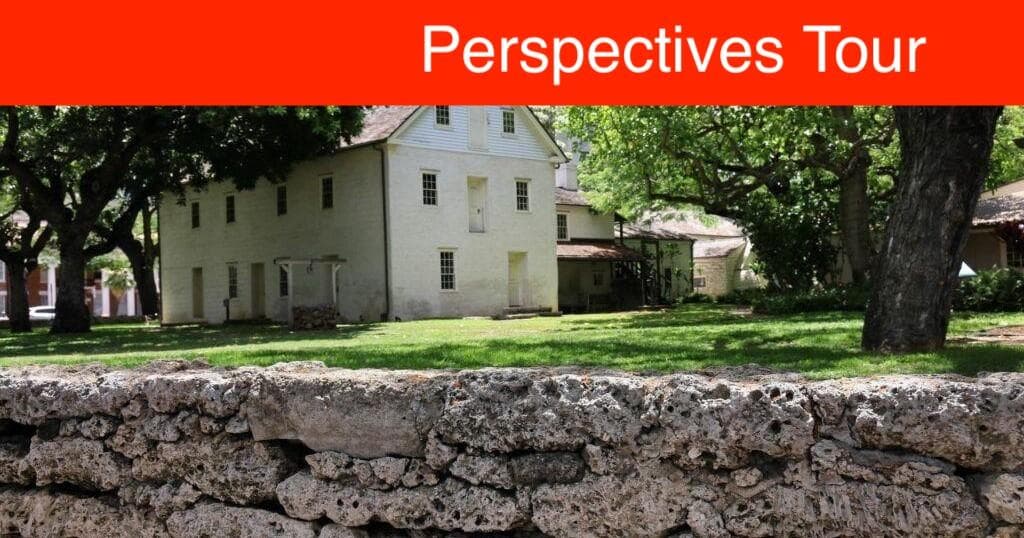 Stone wall foreground with mission house behind, interpretive tour