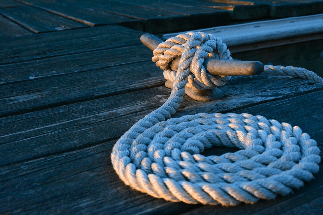 Coiled mooring rope on weathered wooden dock at dusk