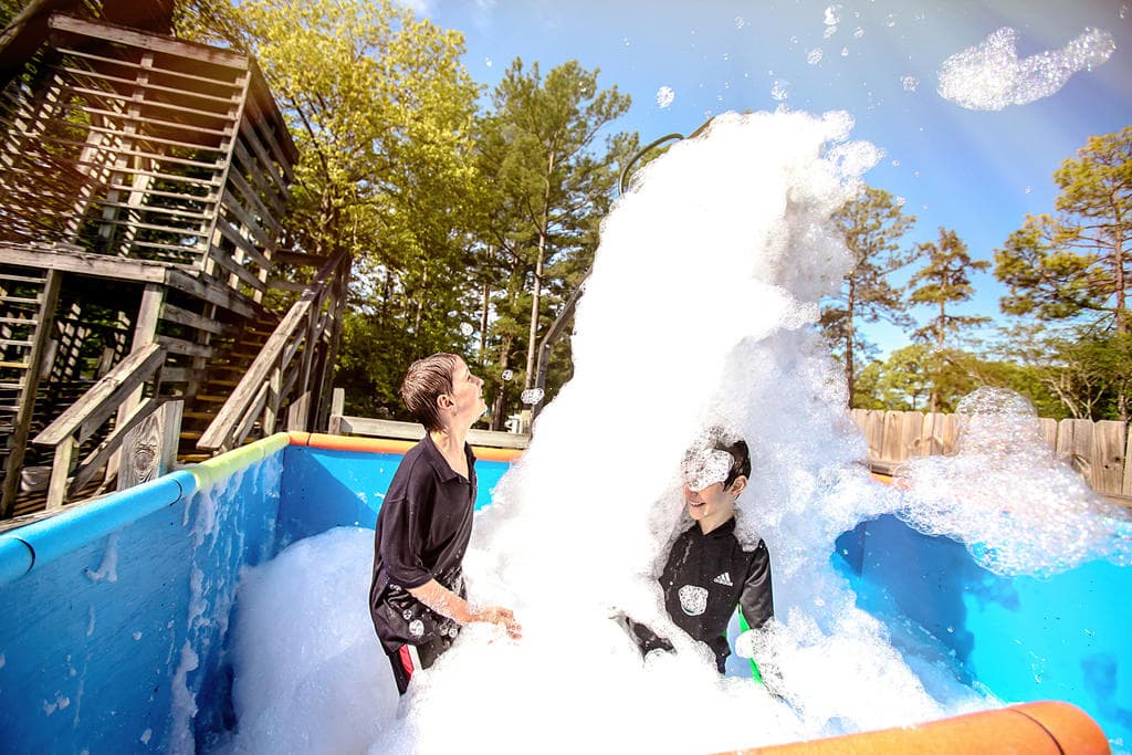 Kids enjoying foam splash water attraction at outdoor park