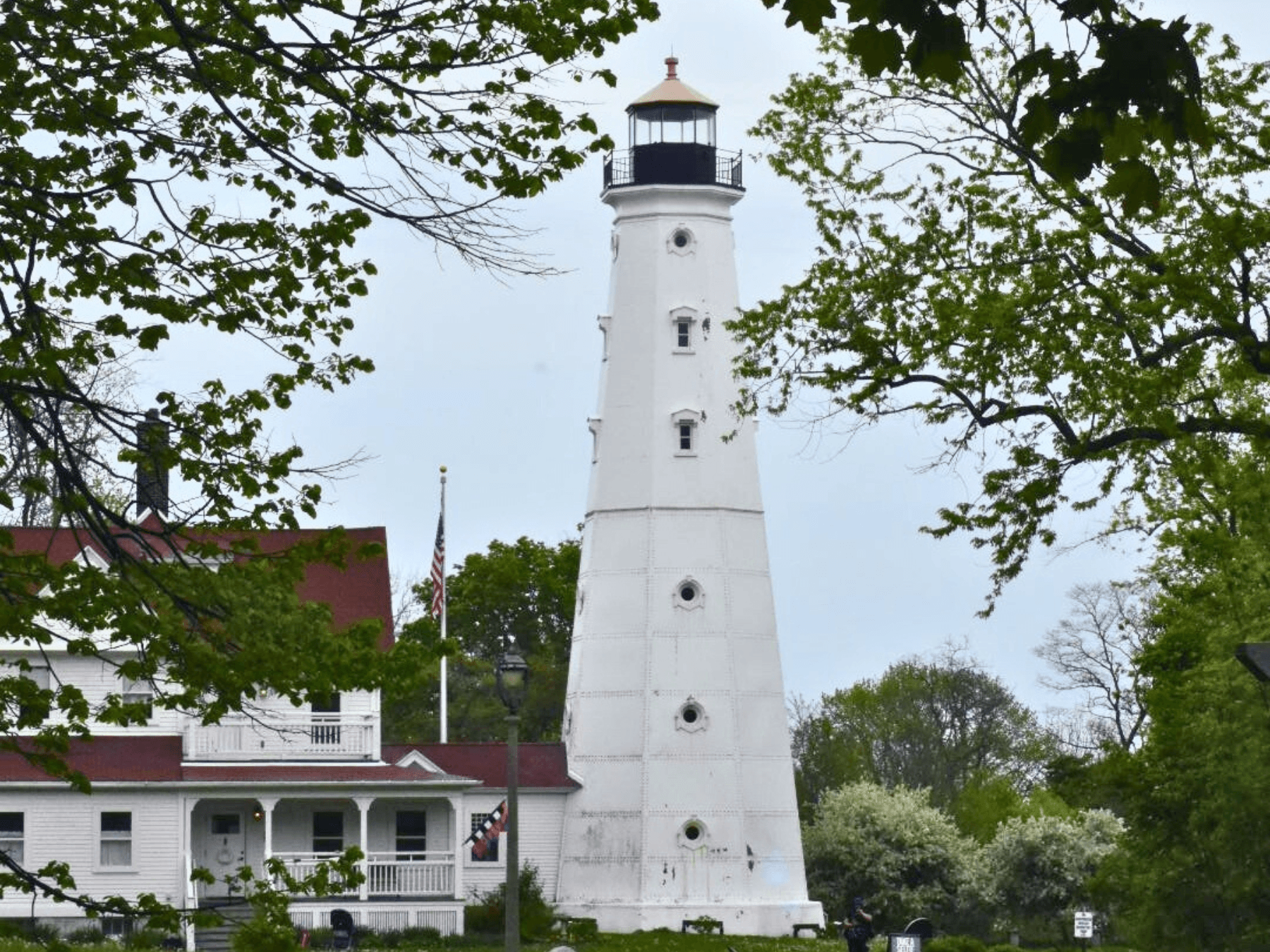 Historic Milwaukee lighthouse on lakeshore with trees and sky