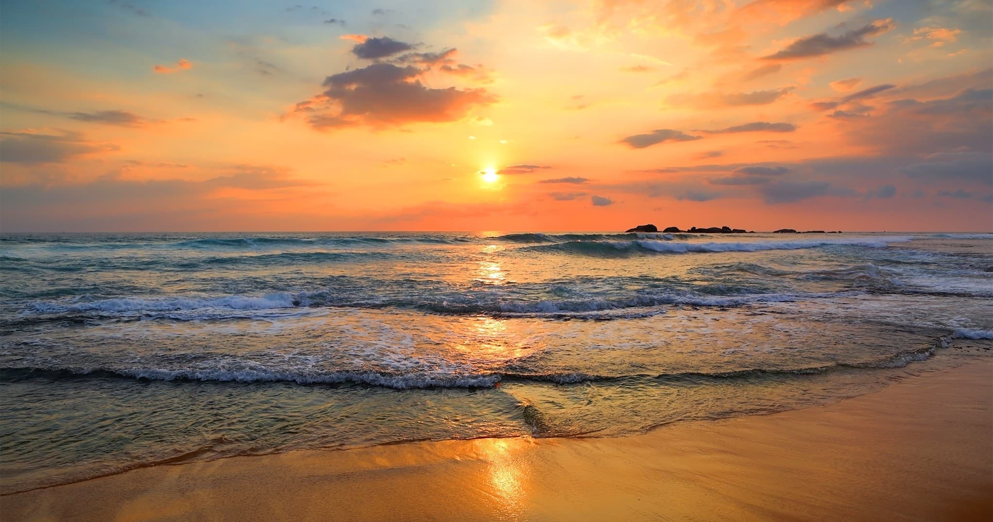 Sunset beach shoreline with gentle waves, coastal sunset view