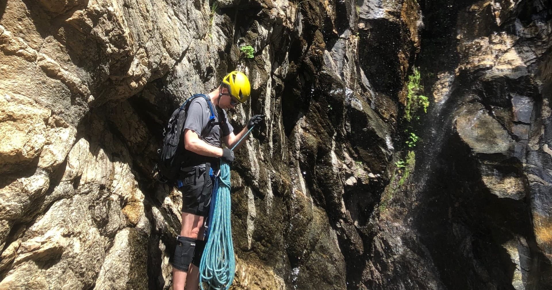 Climber belaying in shaded granite canyon during outdoor climb