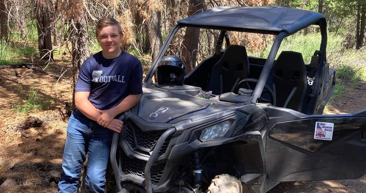 Person posing with UTV in forest clearing for guided trail rides