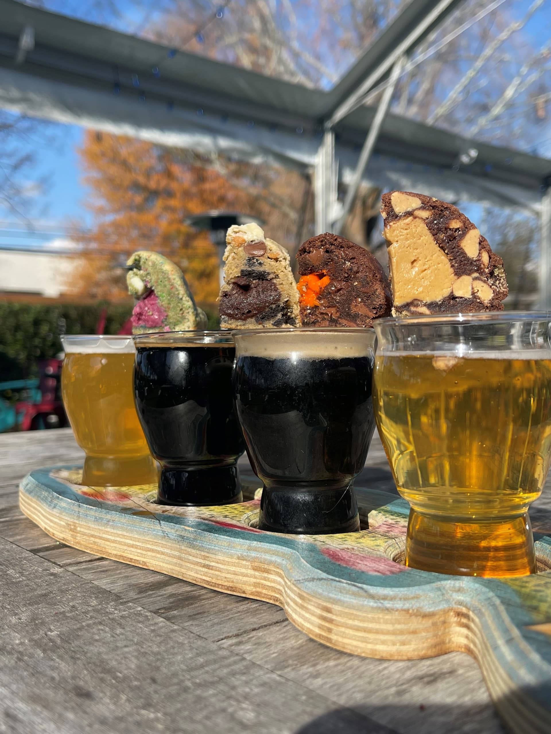 Beer flight tasting outdoors on wooden paddle at brewery patio