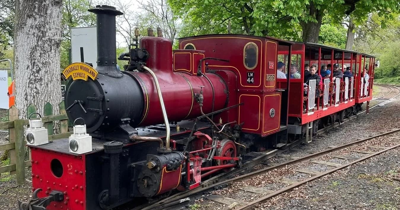 Red heritage steam train on outdoor rural tracks in Ireland