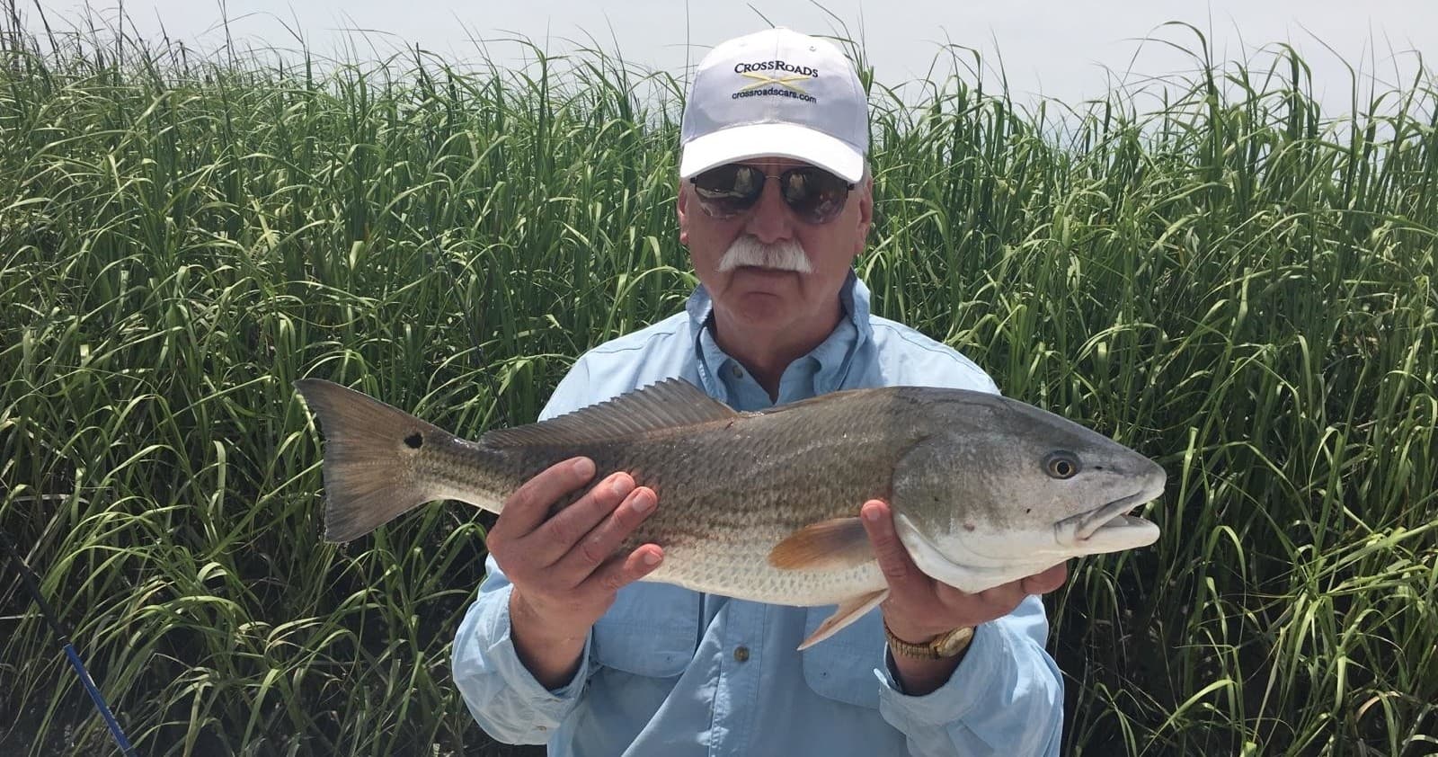 Guide holding caught redfish among Hilton Head marsh grass