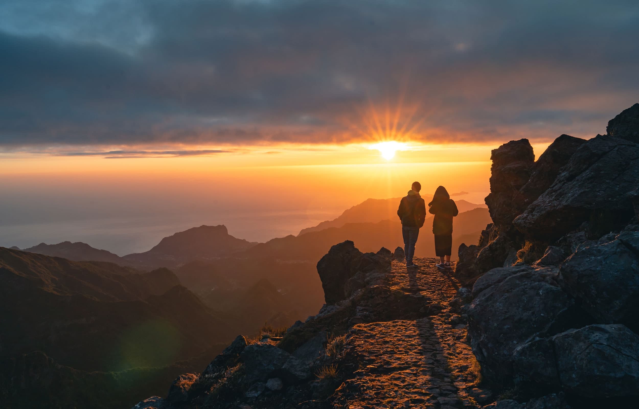 Two hikers watching sunset on Madeira mountain ridge viewpoint