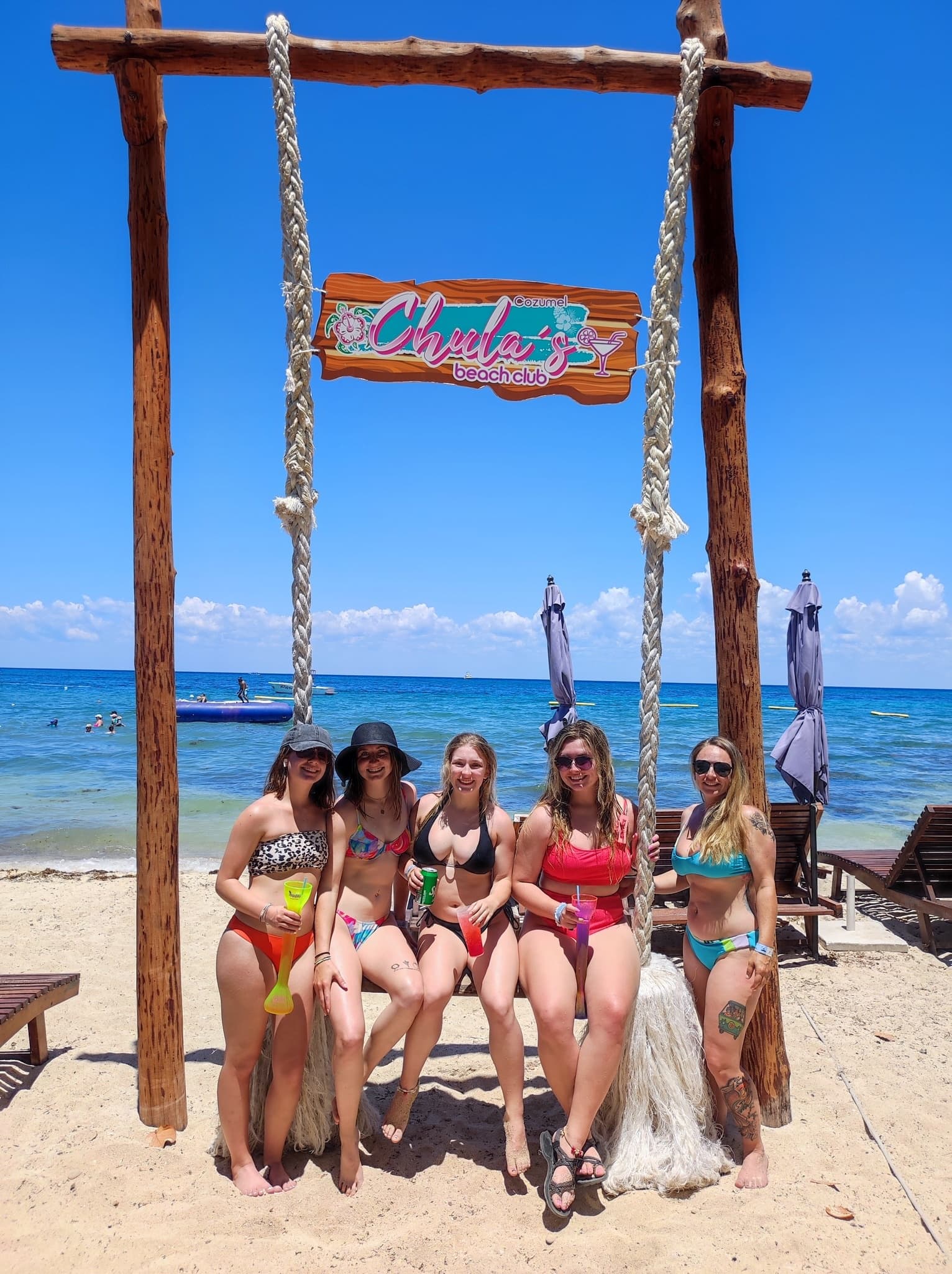 Group of friends on beach swing enjoying sunny Cozumel shoreline