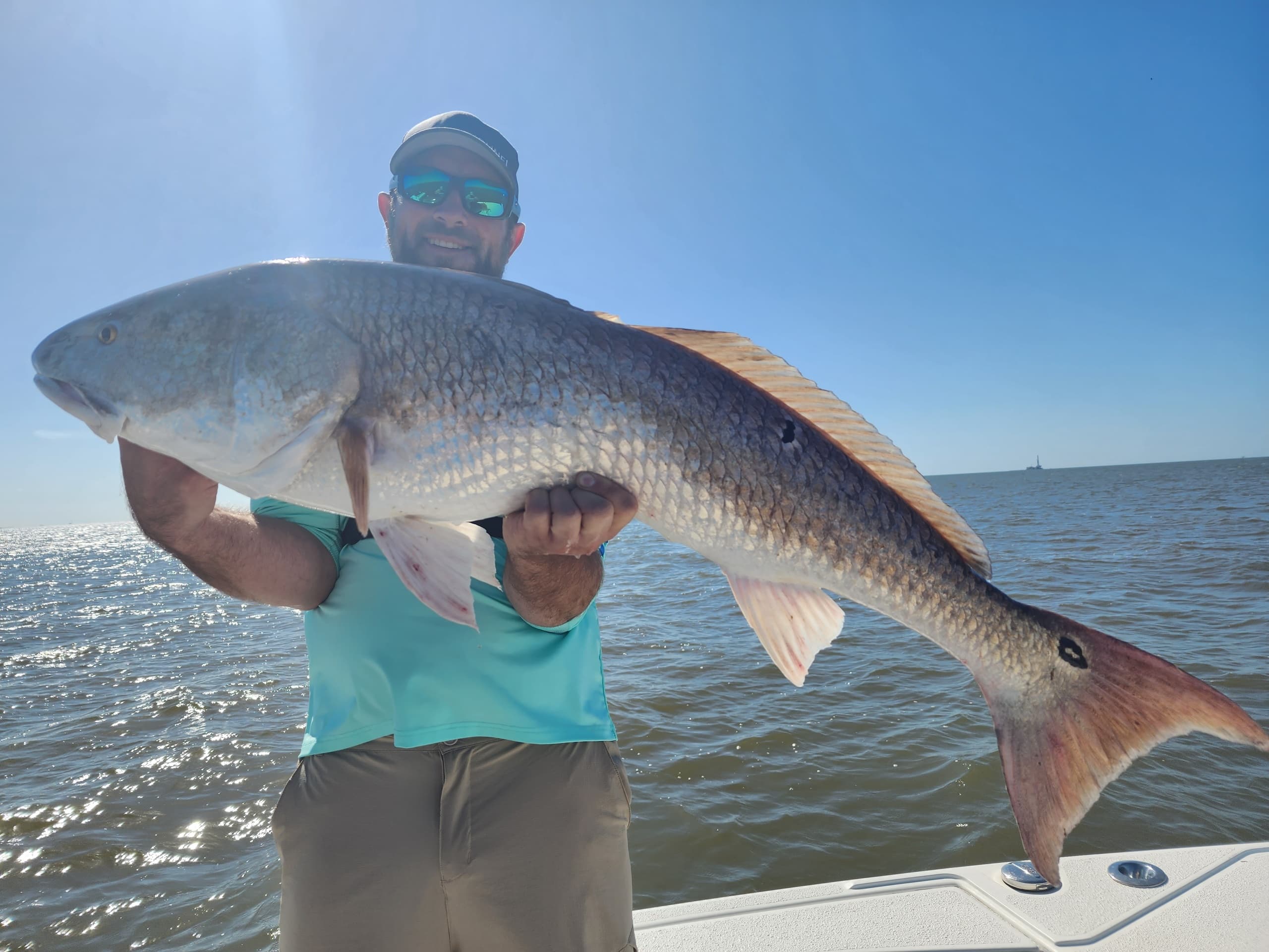 Angler holding large redfish on sunny coastal boat trip