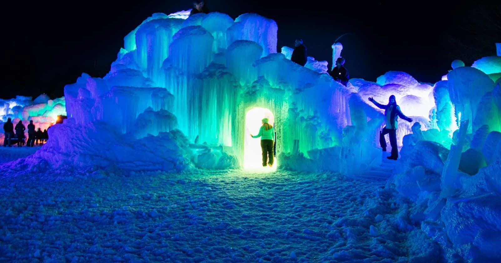 Illuminated ice castle entrance lit with colored lights at night