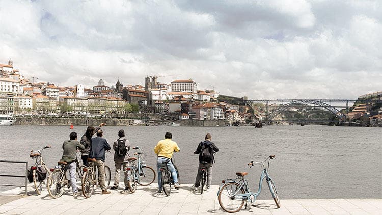 Group of cyclists overlooking wide riverside cityscape and bridge