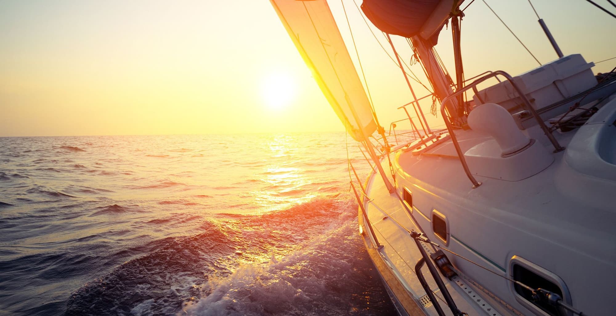 Sailboat cruising at sunset with golden light on open water