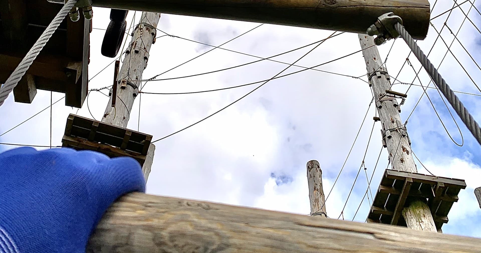 Participant view climbing wooden high ropes poles under blue sky Norderstedt