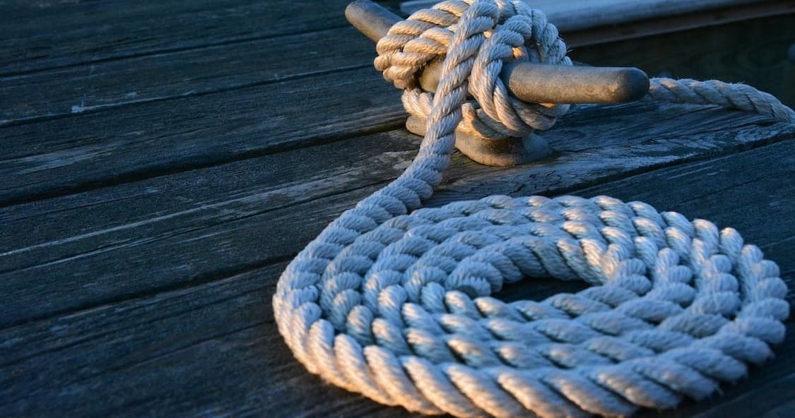 Coiled mooring rope on wooden dock highlighting boat dockage detail
