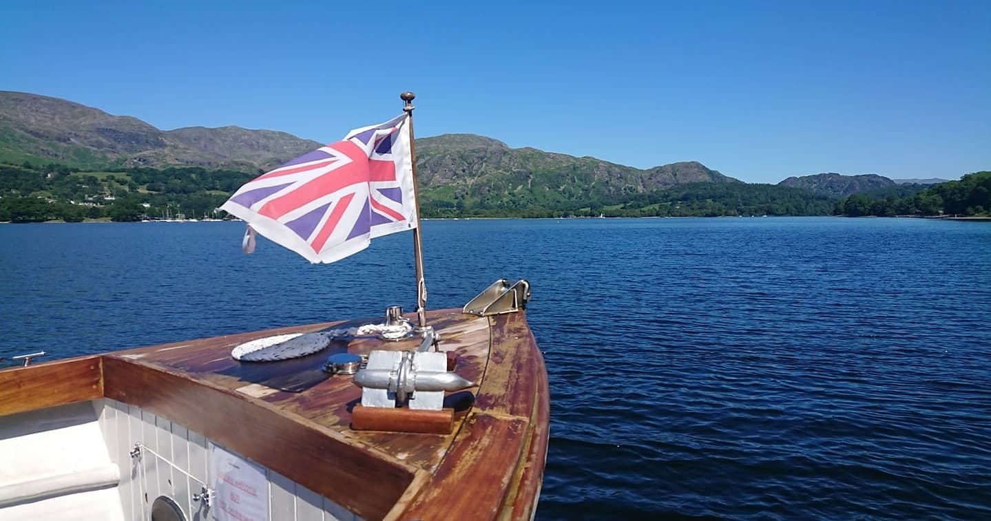 Boat bow with Union Jack on Coniston Water under blue sky