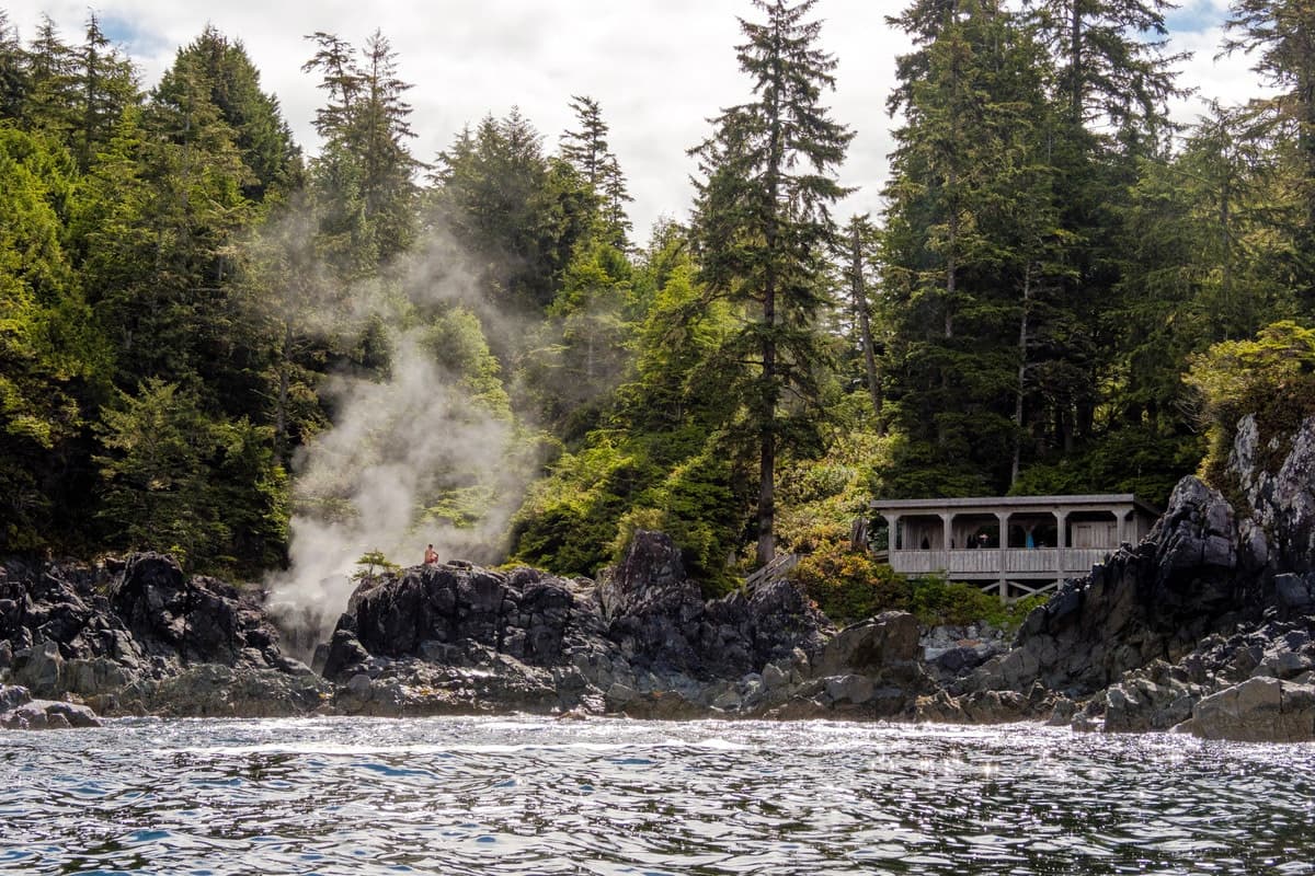 Rocky forest shoreline with steam vents and waterfront lodge