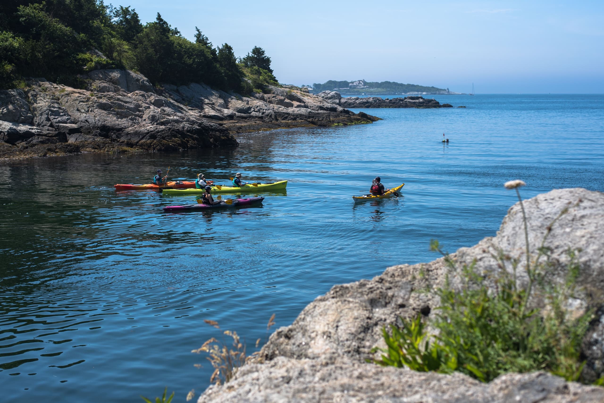 Coastal kayakers exploring rocky shoreline and blue sea