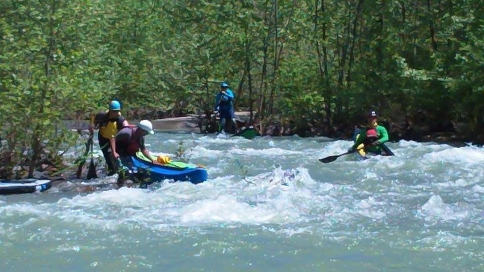 Kayakers navigating forested river rapids in group outing
