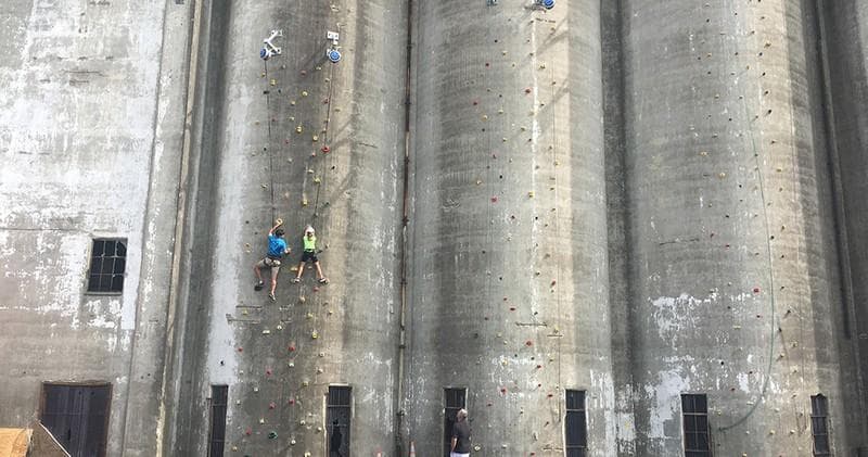 Rock climbers scaling concrete grain silos on riverfront