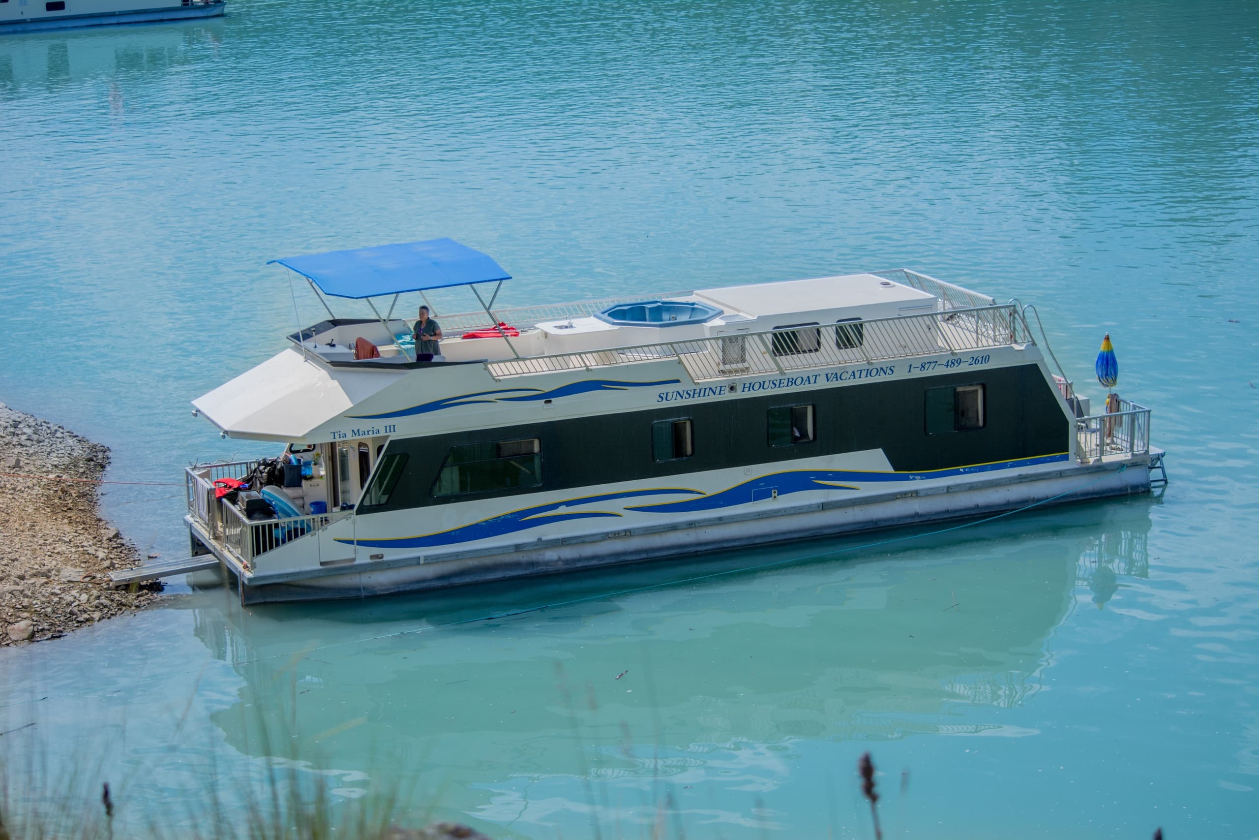 Pontoon boat cruising turquoise reservoir with distant pine shores