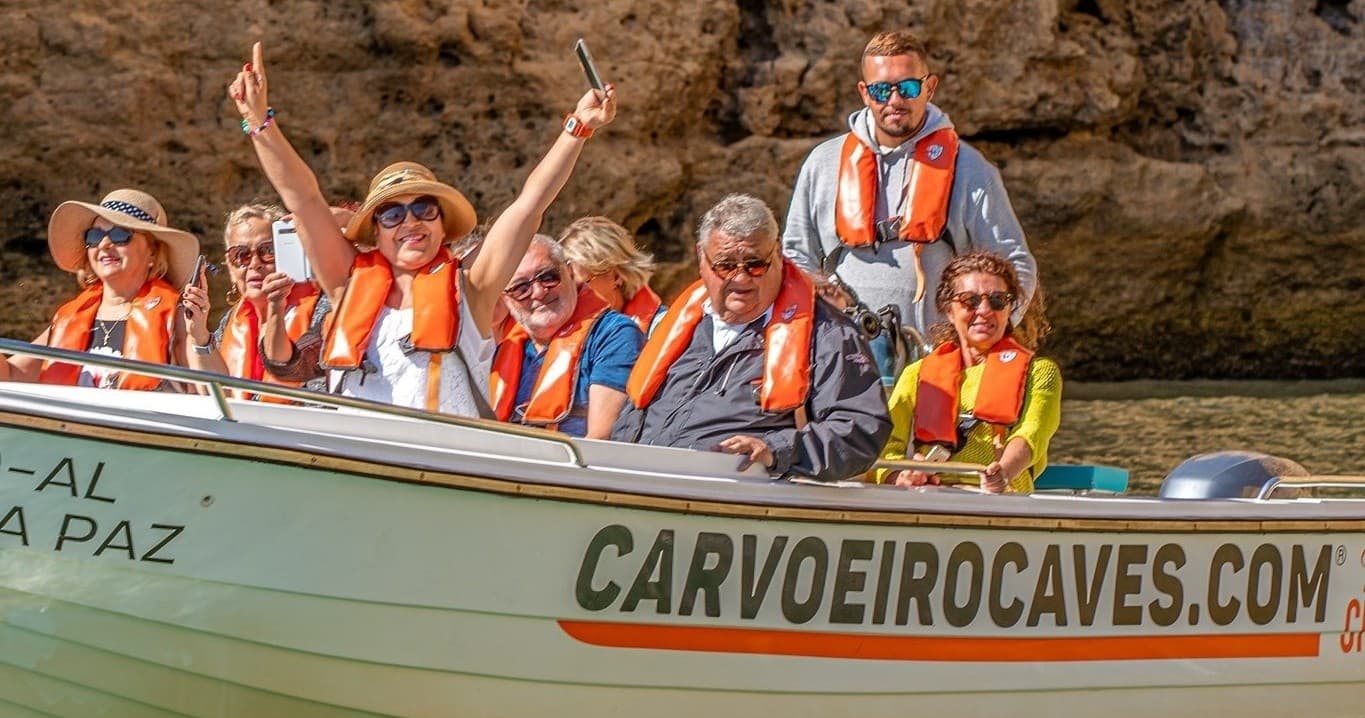 Sightseeing boat with lifejackets near Algarve sea cliffs, tour
